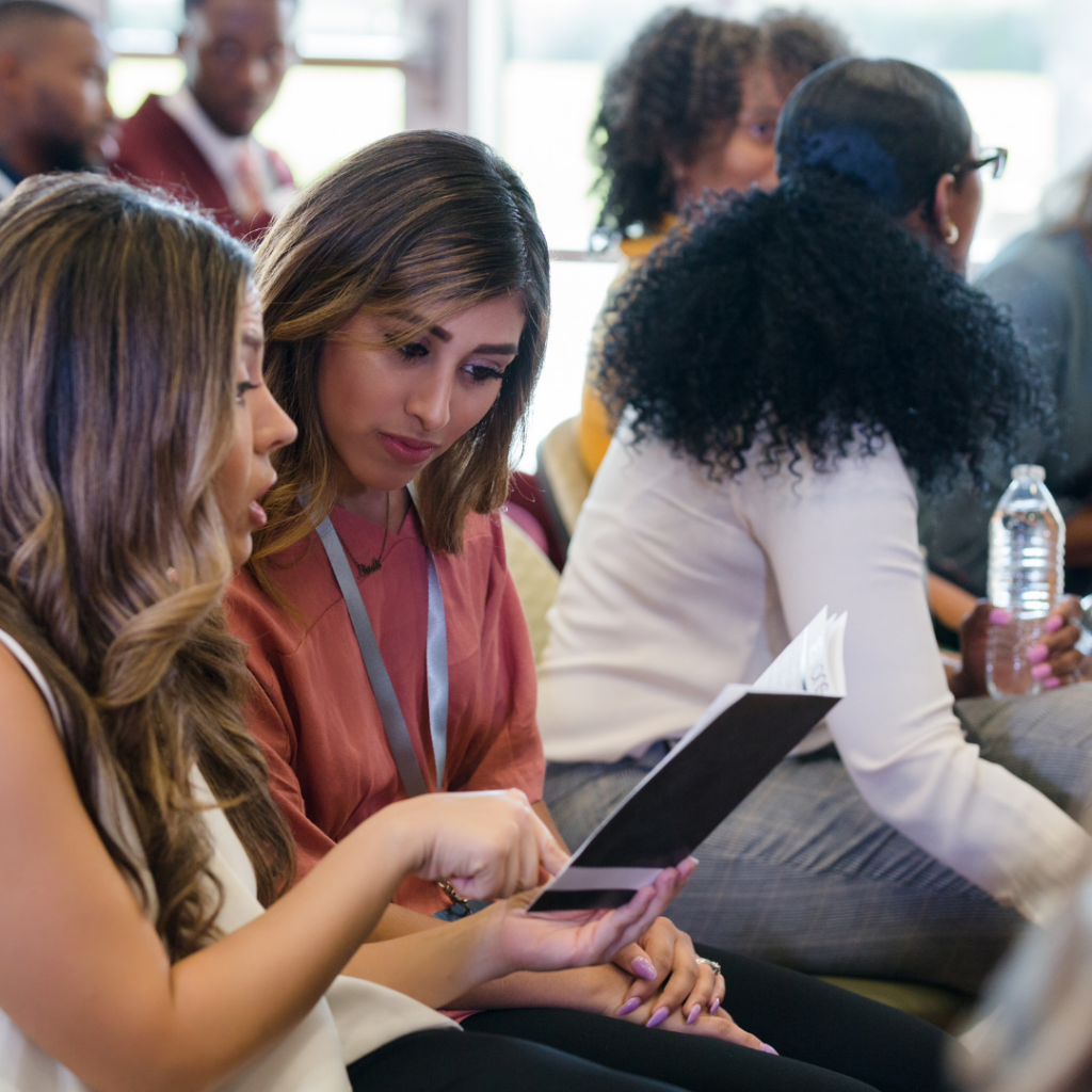 People sitting at a conference and consulting the program