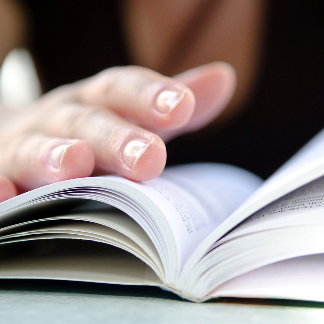 Close up of an open book with a hand holding it open