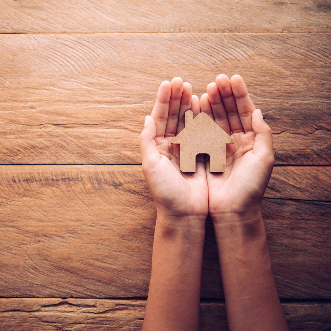 Photo of two hands holding a wooden shaped house