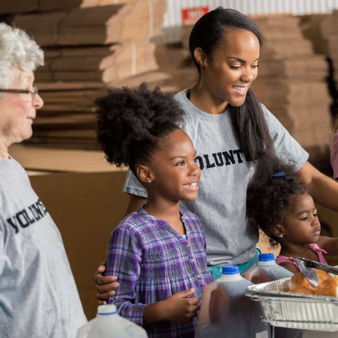 Volunteers in group settings taking food from a buffet