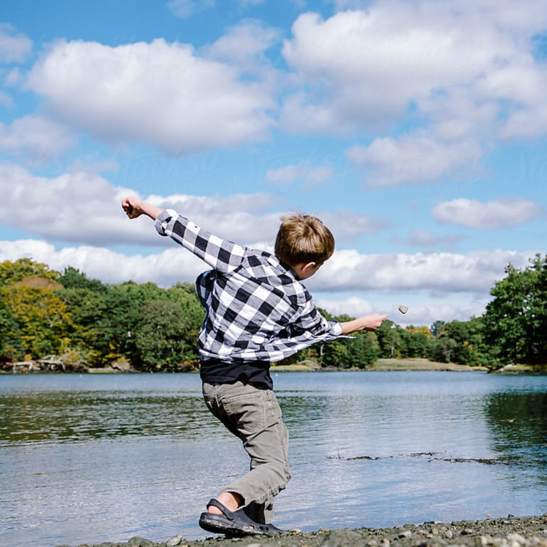 A kid throwing a rock in a river